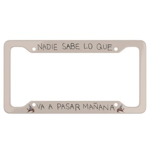 May include: White metal license plate frame with the text "Nadie sabe lo que va a pasar mañana" in black handwriting.