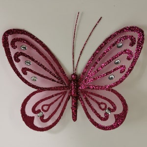 Può includere: Una farfalla rosa con glitter e strass argentati. La farfalla ha un design delicato e intricato ed è perfetta per aggiungere un tocco di brillantezza a qualsiasi progetto di artigianato.