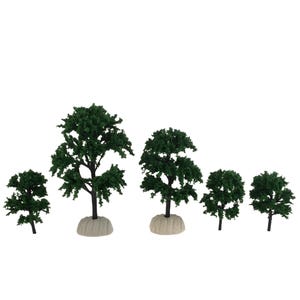 May include: A collection of six miniature model trees with dark green foliage and black trunks. The trees vary in size and shape, with some having a rounded canopy and others more elongated. Each tree is set on a beige base.