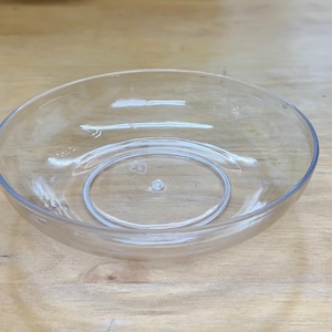 May include: A clear plastic bowl with a smaller bowl inside. The bowl is round and has a smooth surface.