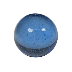 May include: A blue glass marble with a speckled, cloudy appearance.