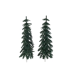 Peut inclure: Deux sapins de Noël artificiels miniatures vert foncé avec des bases blanches sur fond blanc. Les arbres ont une forme classique de conifère avec des branches détaillées et texturées, parfaits pour les décorations de fêtes ou les projets d'artisanat.