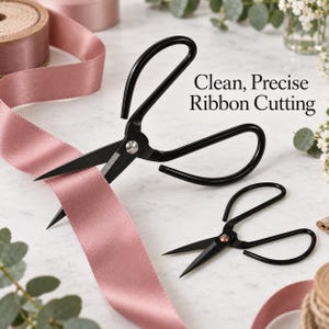 May include: Two pairs of black metal scissors with pointed blades and large looped handles, positioned next to a spool of dusty pink satin ribbon. The text Clean, Precise Ribbon Cutting is printed in black on the white surface near the scissors.