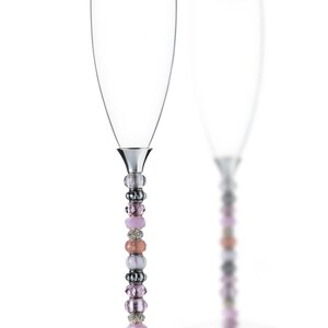 Puede incluir: Dos copas de champán con tallos de cuentas. Las cuentas son de color rosa, melocotón, blanco y plateado.