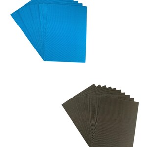 May include: Two stacks of cardboard sheets, one blue and one black. The sheets are corrugated and have a textured surface.