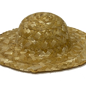 May include: A woven straw hat with a wide brim and a rounded crown. The hat is light brown in colour and has a natural, rustic look.