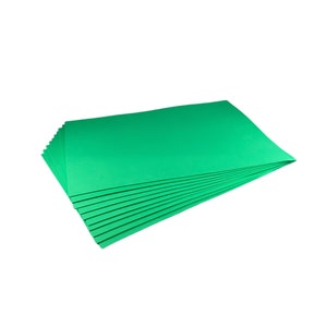 Puede incluir: Una pila de hojas rectangulares de color verde brillante, posiblemente papel o cartulina, sobre un fondo blanco. Las hojas est&aacute;n cuidadosamente dispuestas, con sus bordes visibles, lo que sugiere una presentaci&oacute;n limpia y organizada. El color es vibrante y uniforme.