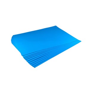 Puede incluir: Una pila de hojas de papel azul brillante, probablemente para manualidades u oficina, se muestra sobre un fondo blanco. El papel tiene una textura suave y un color s&oacute;lido vibrante. La pila est&aacute; cuidadosamente organizada.