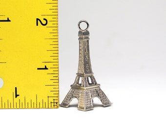 May include: Silver Eiffel Tower charm, approximately 1 inch tall, with a loop at the top for attaching to a necklace or bracelet.