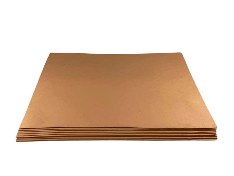 Puede incluir: Una pila de hojas de papel rectangulares de color marr&oacute;n claro. Las hojas est&aacute;n apiladas ordenadamente, con los bordes alineados. El papel tiene un acabado liso y mate y parece ser de grosor medio. El fondo es blanco liso.