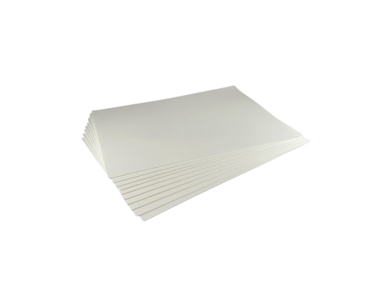 Puede incluir: Una pila de hojas de papel rectangulares de color blanquecino. El papel est&aacute; dispuesto de forma ligeramente abanicada, revelando las hojas individuales. Los bordes son limpios y el papel parece tener una textura suave.