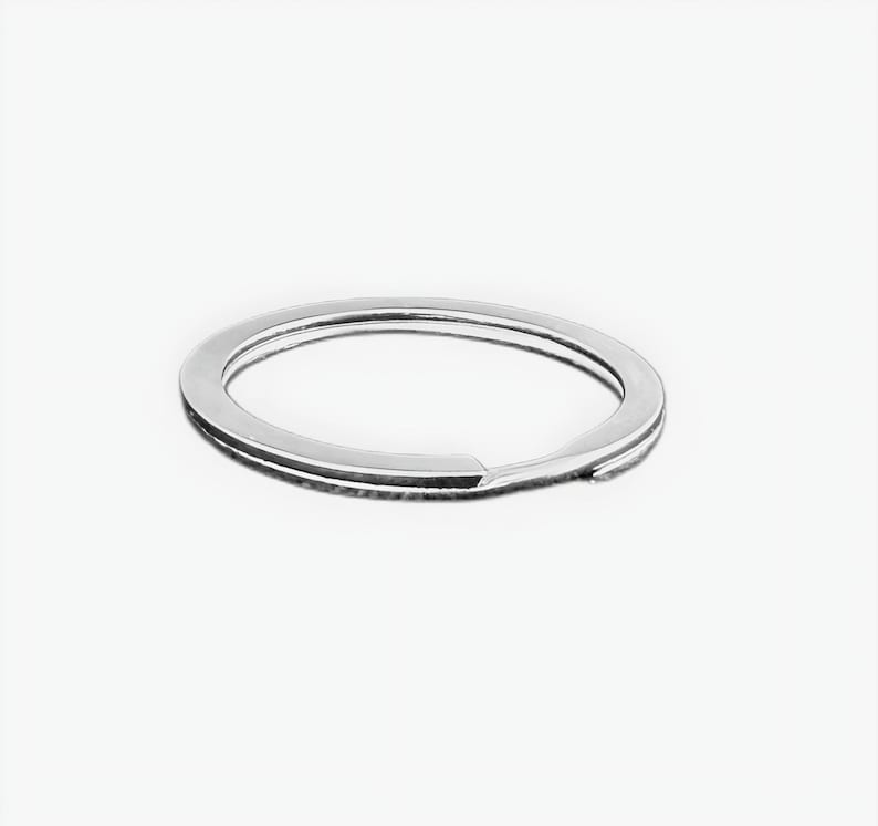 May include: A shiny, silver-colored split key ring. The key ring is circular with a split for adding keys. The key ring is made of metal and is shown against a white background.