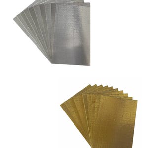 May include: Two stacks of decorative metallic placemats. One stack is silver and the other is gold. Each stack has 10 placemats.