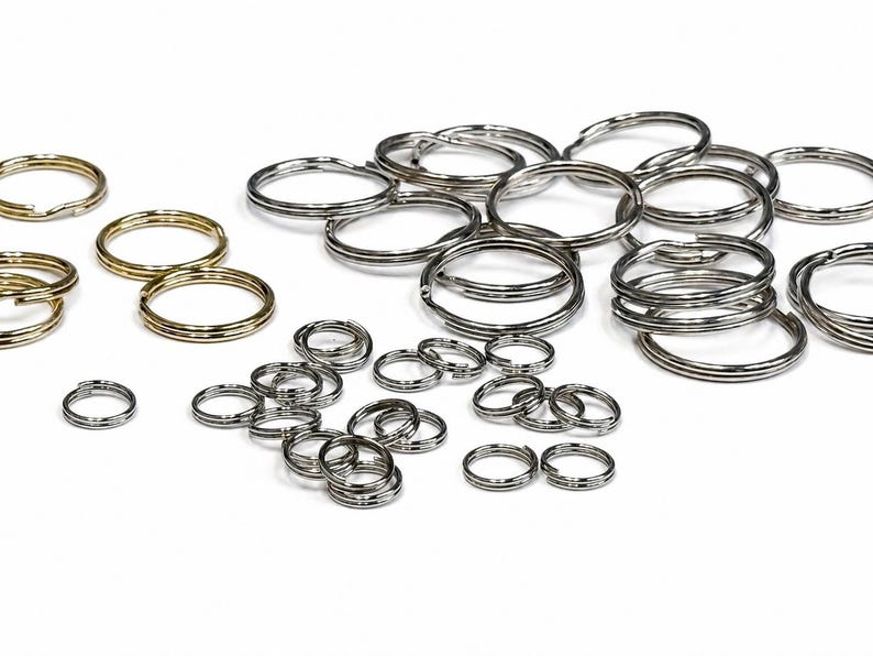 May include: A collection of split key rings in various sizes and finishes. Some are gold-toned, while others are silver-toned. The key rings are made of metal and are arranged on a white background. They are suitable for organizing keys or crafting.