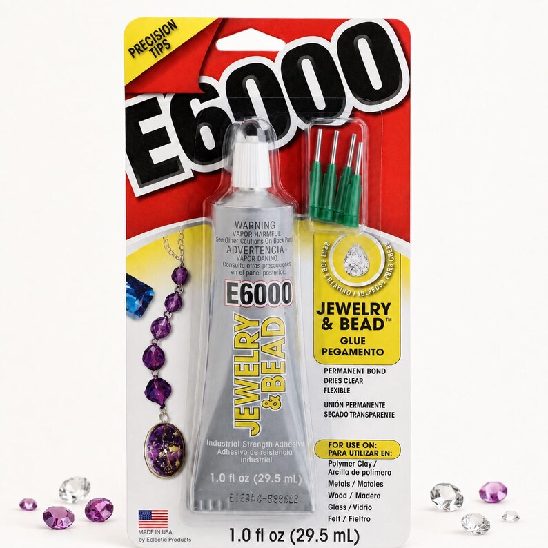Puede incluir: Un tubo de 29,5 ml de adhesivo E6000 Jewelry & Bead en su empaque original. El tubo plateado incluye cuatro puntas de precisi&oacute;n verdes. La tarjeta roja y amarilla presenta texto, un gr&aacute;fico de un collar de cuentas moradas y cristales.