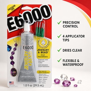 May include: A tube of E6000 Jewelry & Bead adhesive in its retail packaging, featuring four green precision applicator tips. The packaging displays the product name, a 29.5 ml volume, and lists features including precision control and waterproof properties.