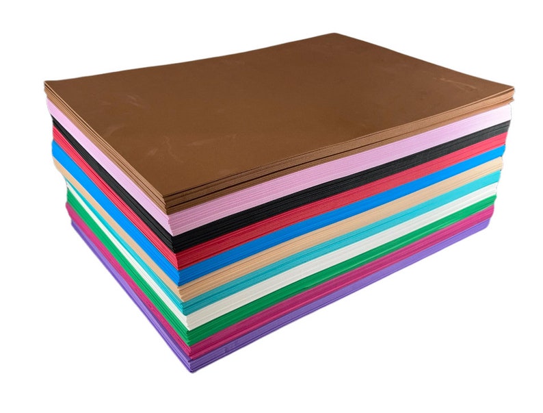 Puede incluir: Una pila de papel de cartulina de colores en varios tonos, incluyendo marr&oacute;n, rosa, negro, rojo, azul, beige, turquesa, blanco, verde, magenta y morado. La hoja marr&oacute;n est&aacute; en la parte superior.