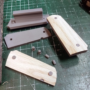 May include: A set of unfinished wooden knife scales with gray plastic spacers and small gray plastic pins. The scales are ready to be sanded and finished.