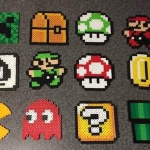May include: A collection of 12 pixel art designs, each made with colorful beads. The designs include a green Minecraft creeper, a yellow and brown treasure chest, a green and white mushroom, a red and white mushroom, a red and white Mario character, a gold coin, a yellow Pac-Man, a red ghost, a yellow and brown question block, and a green pipe.