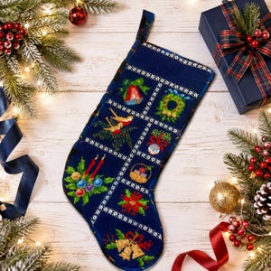 May include: A navy blue Christmas stocking featuring a grid pattern with embroidered holiday motifs including a bell, wreath, birds, ornament, gift basket, poinsettia, candles, and golden bells, finished with a dark blue fabric hanging loop.