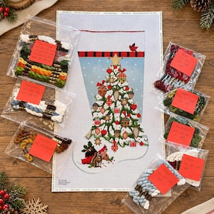 May include: A needlepoint canvas of a Christmas stocking featuring a decorated tree with ornaments, a cardinal, and a squirrel, accompanied by several clear plastic bags containing assorted embroidery floss skeins with red labels.