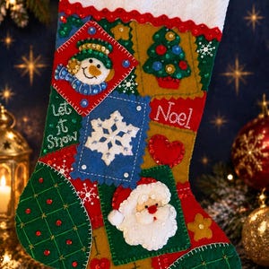 May include: A felt Christmas stocking featuring a white cuff with a red bow. The body displays patchwork squares with appliqués of a snowman, a Christmas tree, a snowflake, and Santa Claus. Text reads Let it Snow, Noel, and Santa with red sequins.