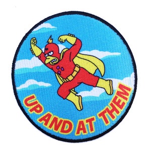May include: A round, blue and yellow embroidered patch with a cartoon character in a red and yellow superhero costume flying through the air. The text "UP AND AT THEM" is written around the character.