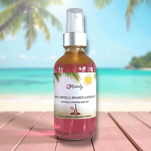 May include: A glass bottle of body mist with a silver spray top. The bottle contains a pink liquid with a gold top layer. The label reads "Médaly" and "Soothing & Hydrating Body Mist". The background is a beach scene.