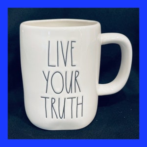 May include: White ceramic coffee mug with a black outline of the text "Live Your Truth" on the front.