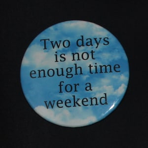 May include: A blue and white button with a white cloud background and black text that reads "Two days is not enough time for a weekend."