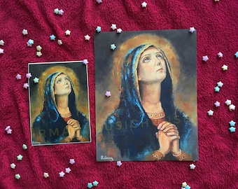 May include: A painting of a woman with her hands clasped in prayer. She is wearing a blue robe and has a halo around her head. The painting is on a white background.