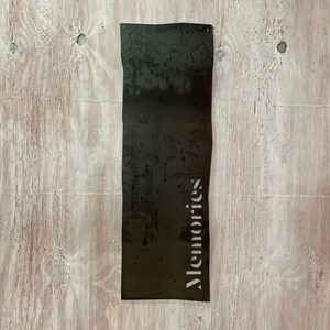 Puede incluir: Un letrero de metal negro con la palabra "Memories" recortada en una fuente decorativa.