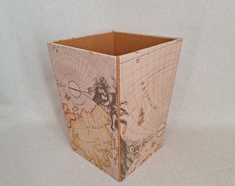 May include: A square wastebasket with a vintage map design. The exterior features a light brown and beige world map with detailed illustrations and text. The interior is a solid tan color, and the seams are stitched with a gold thread.