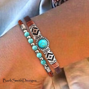 May include: A double-strand bracelet set featuring one strand of small turquoise beads with silver spacers and a second strand of brown leather with a central silver-toned circular turquoise stone and geometric silver accents.
