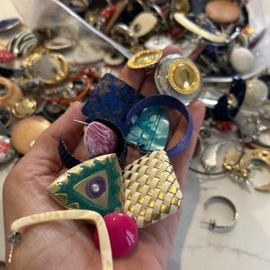 Puede incluir: Una colecci&oacute;n de pendientes vintage de diversas formas, colores y materiales. Los pendientes incluyen formas geom&eacute;tricas, dise&ntilde;os tejidos y piedras de colores.