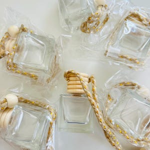 May include: Six clear glass square bottles with wooden tops and gold string attached. The bottles are packaged in clear plastic bags.