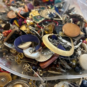 Puede incluir: Una gran bolsa de pl&aacute;stico llena de una variedad de pendientes vintage. Los pendientes est&aacute;n hechos de diferentes materiales, incluyendo metal, pl&aacute;stico, madera y vidrio. Vienen en una variedad de colores, incluyendo oro, plata, rojo, azul, verde y marr&oacute;n.