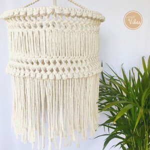 May include: A white macrame lampshade with a fringe bottom. The lampshade is hanging from a white ceiling. The text "HOME Vibes" is visible in the upper right corner of the image.