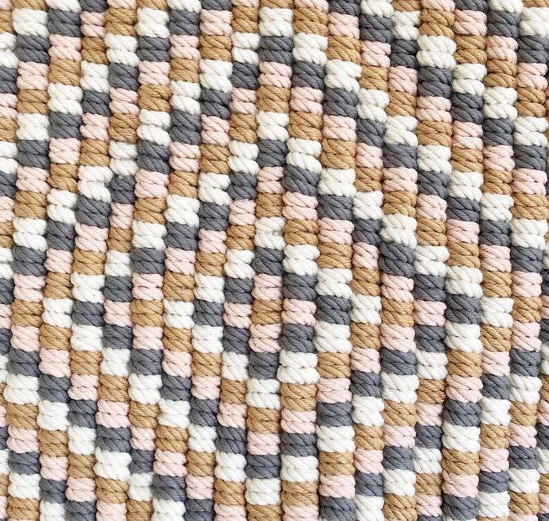 Peut inclure: Gros plan sur un tapis tiss&eacute; avec un motif de rayures de couleur beige, rose, blanc et gris.