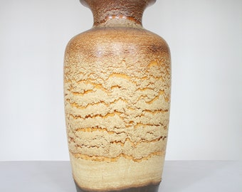May include: A brown and beige ceramic vase with a wavy pattern. The vase has a wide mouth and a narrow base.
