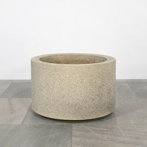 May include: A large, round, concrete planter with a rough, textured surface. The planter is light gray in color and has a slightly rounded bottom.