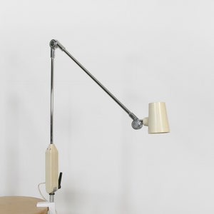 May include: A chrome and white adjustable desk lamp with a clamp base. The lamp has a long, articulated arm and a white shade.