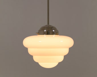 May include: A white glass pendant light with a layered, rounded design. The light is suspended from a silver cord and has a silver metal fixture.
