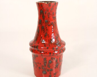 May include: A red ceramic vase with a speckled glaze. The vase has a narrow neck and a wide base.
