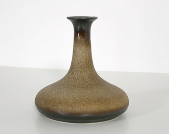 May include: A brown ceramic vase with a flared base and a narrow neck. The vase has a mottled brown glaze with a darker brown rim.