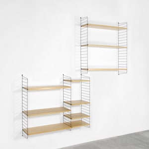 May include: Two black metal wall shelves with wooden shelves. The shelves are stacked on top of each other and are attached to a white wall.