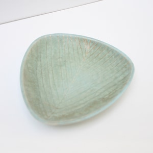 May include: A light blue triangular ceramic dish with a subtle textured pattern and gold accents.