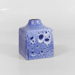May include: A blue and white ceramic vase with a textured surface. The vase has a square shape and a wide opening.