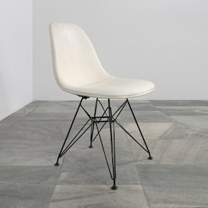 May include: A white molded plastic chair with a black metal frame. The chair has a curved back and a slightly angled seat.