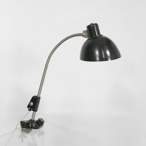 May include: A black desk lamp with a flexible arm and a clamp base. The lamp has a black metal shade and a silver metal arm.